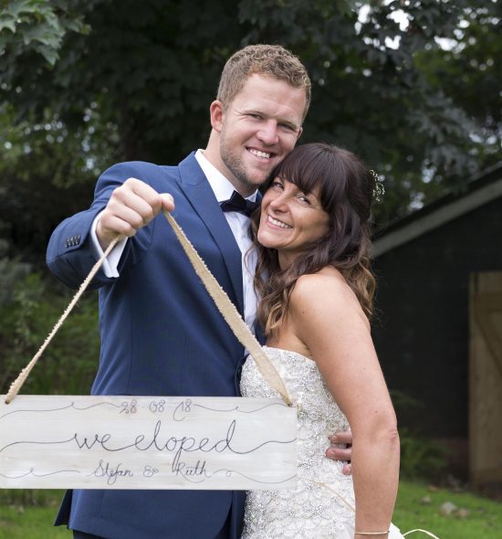 Ruth and Stefan holding an elopement sign after getting married at the Cow Shed